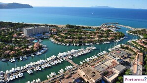 An aerial view of a marina with numerous boats docked, surrounded by residential buildings and a large hotel.