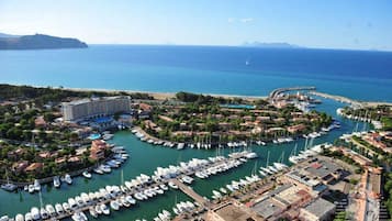 An aerial view of a marina with numerous boats docked, surrounded by residential buildings and a large hotel.