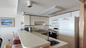 Une cuisine compacte dotée d’un îlot central, d’un four à micro-ondes, d’un réfrigérateur et d’un évier.
