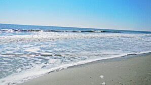 Une plage où les vagues viennent doucement lécher le rivage.