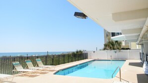 Un espace piscine avec des chaises longues et vue sur la mer.