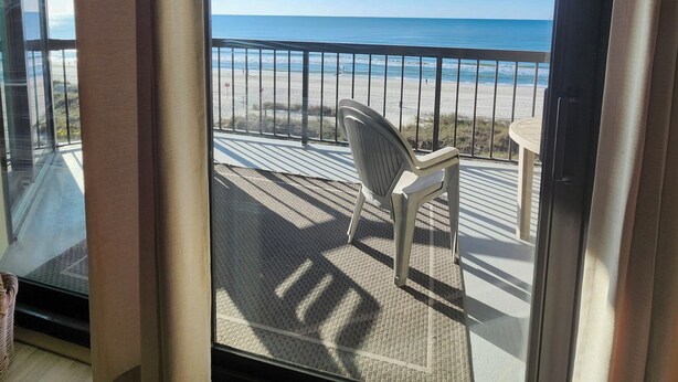 Un balcon avec vue sur la plage et l’océan.