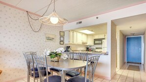 A dining area with a round table, six chairs, and a hanging light fixture.
