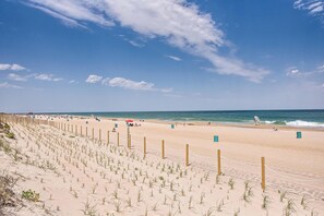 Una playa arenosa con una cerca de madera y una torre de salvavidas.
