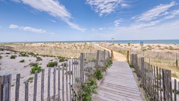 A wooden boardwalk leading to a beach with a clear sky.