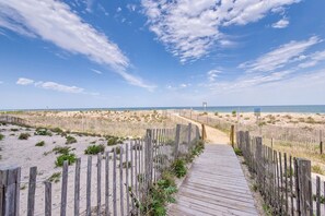 Une promenade en bois menant à une plage, avec un ciel dégagé.