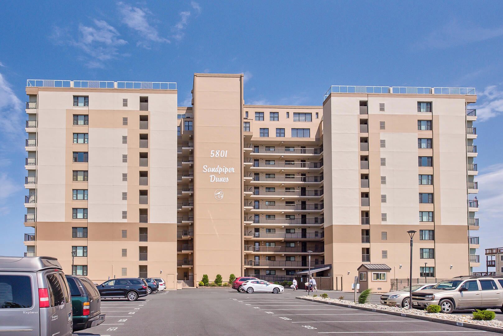 A high-rise building with multiple balconies, labeled "5801 Sandpiper Dunes."