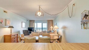 Une chambre d’hôtel avec un coin repas, une télévision et un balcon offrant une vue.