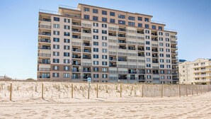Un hôtel à plusieurs étages, doté de balcons, situé près d’une plage de sable.