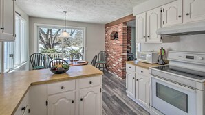 A kitchen with white cabinets, a brick fireplace, a microwave, and a large oven. - Parsonsfield Vacation Rental Near Skiing & Lakes! (Parsonsfield)
