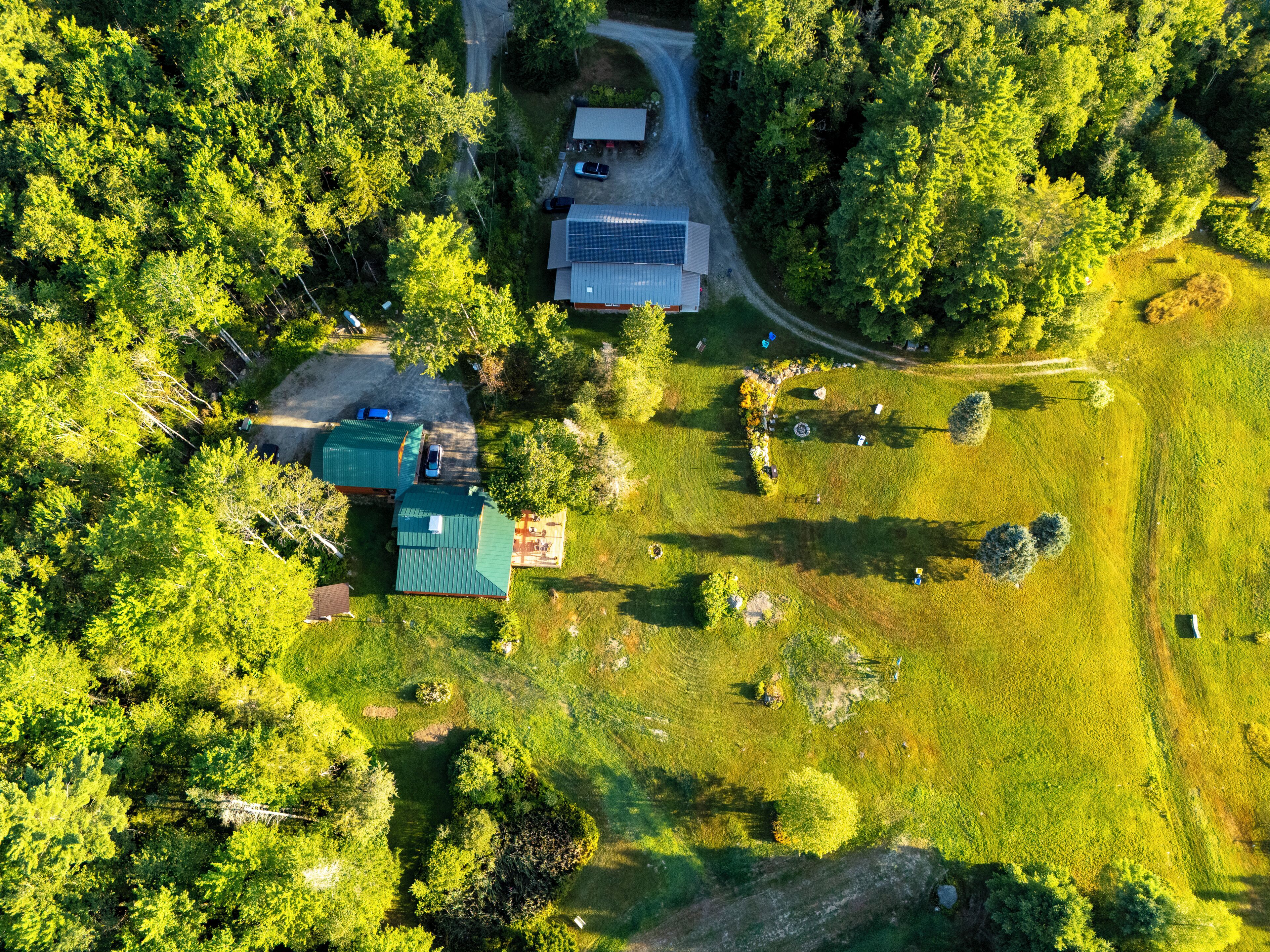 An aerial view of a residential area with houses, a solar panel installation, and a grassy field.