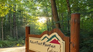 A wooden sign for Robert Frost Mountain Cabins with a mountain and house graphic. - Adorable cabin with screened porch and private fire pit (Ripton)