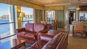 A hotel room with a leather sofa, dining table, chairs, and a view of a body of water. - Platinum Presidential Lock-Off Villa on the Lake-Westgate Lakes Orl. Sleeps 16 (Orlando)