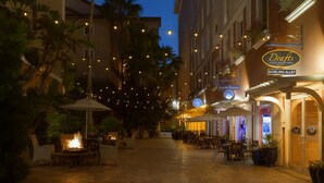 An outdoor dining area with string lights, tables, and chairs, and a building with a sign for 'Drafts Sports Bar & Grill' on Bowling Alley. - Platinum Presidential Lock-Off Villa on the Lake-Westgate Lakes Orl. Sleeps 16 (Orlando)