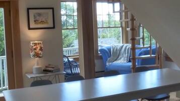 A modern kitchen with a central island, a dining area with bar stools, and a staircase leading to an upper level.