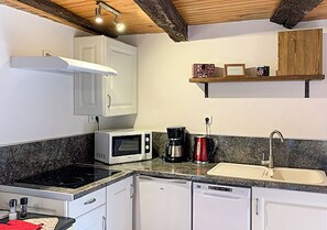 A compact kitchen with white cabinets, a microwave, a coffee maker, and a dishwasher.