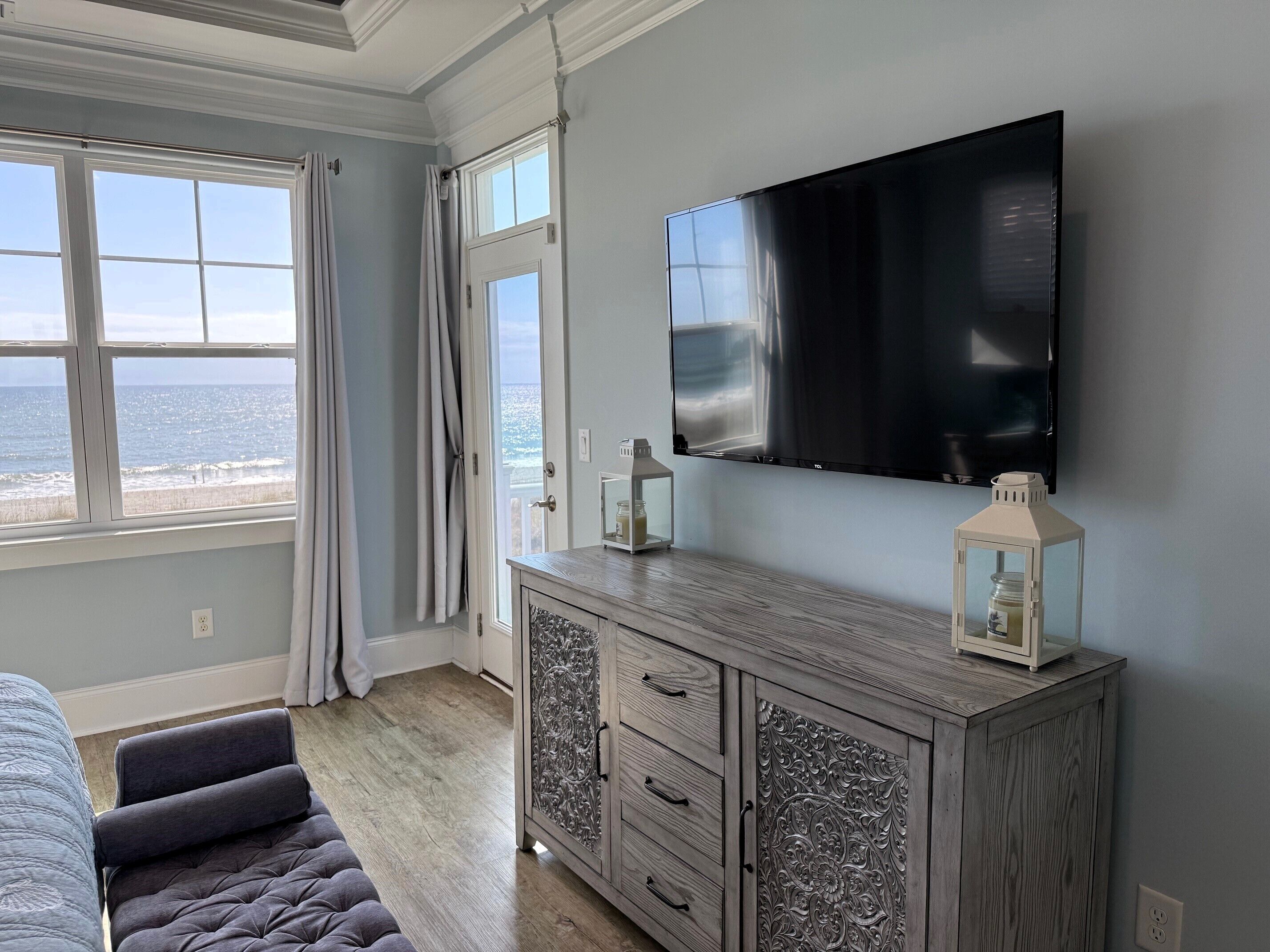 Une chambre dotée d’une grande fenêtre, d’un téléviseur à écran plat, d’une armoire en bois et d’un banc rembourré.