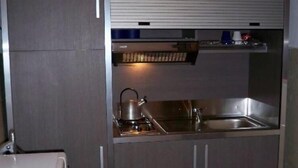 Une cuisine compacte équipée d’une cuisinière intégrée, d’un évier et d’un four à micro-ondes.