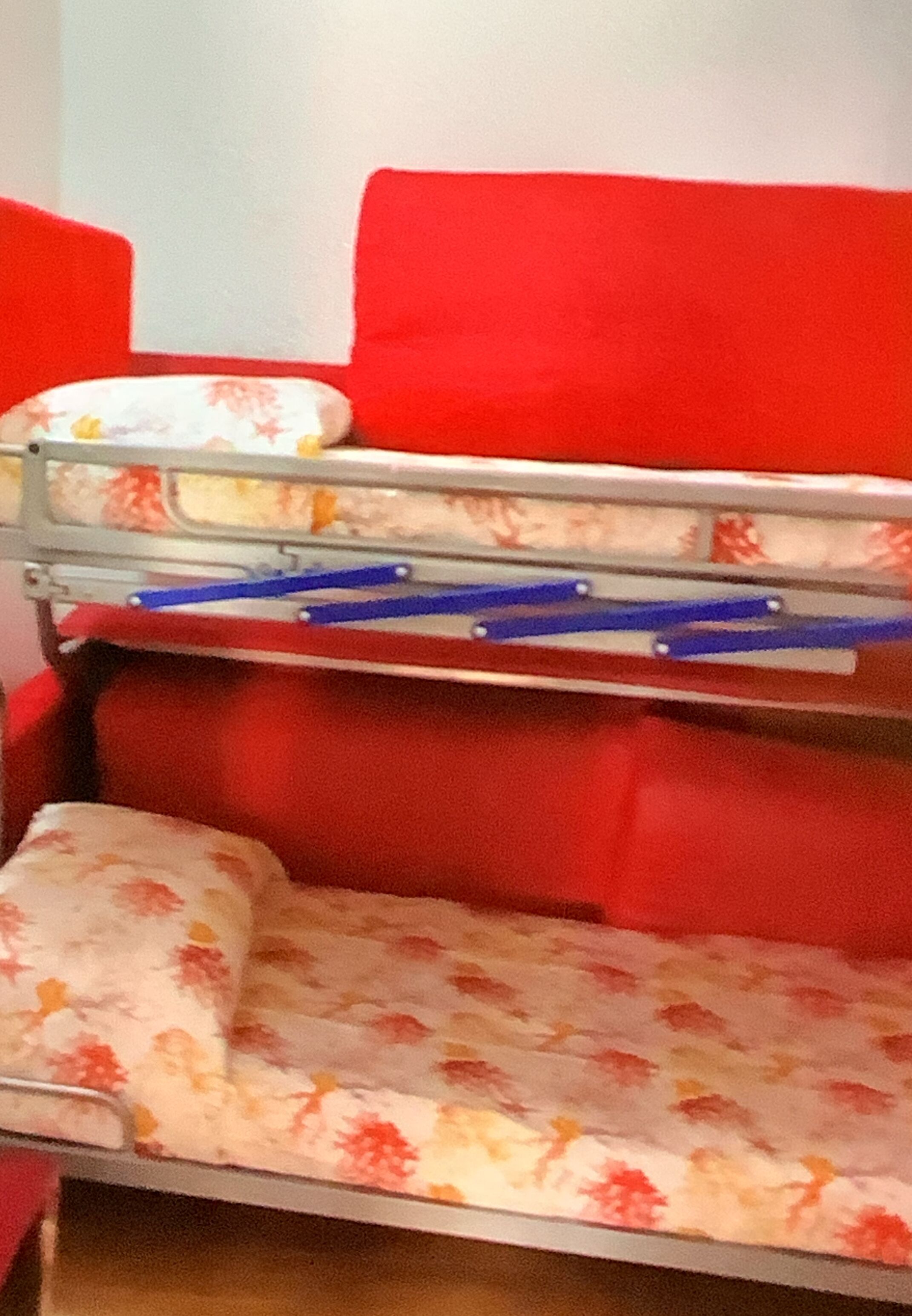 A bunk bed with red cushions and floral-patterned bedding.