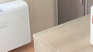 Une pièce avec un appareil électroménager blanc, un meuble beige et une table beige.