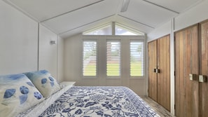 A bedroom with a bed, a wooden wardrobe, and a window with shutters.