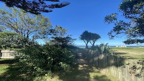 A fenced outdoor area with trees and a clear view of the ocean.
