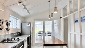 A modern kitchen with stainless steel appliances, a wooden countertop, and pendant lighting.