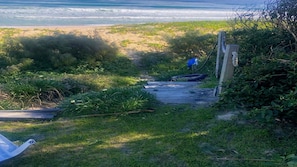 A pathway leading to a beach with a wooden structure and a blue object on the grass. - Jack s Cottage - perfect Wooli escape (Wooli)