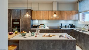 A modern kitchen with a central island, wooden cabinets, and pendant lighting. - Rawlinson Road 10B | Oxford Holiday Let | 2 Beds & Sleeps 4 (Oxford)