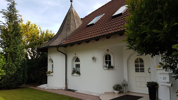 A traditional house with a tiled roof, white walls, and a small garden.