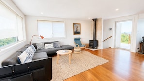 A modern living room with a sofa, armchair, and a fireplace. - Minnie Beach House, TOP NOTCH (Minnie Water)