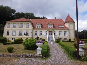 A large, two-story building with a red-tiled roof and multiple windows. - Gutshaus Wohlenhage - Fewo 3: Max. 6 persons (63 m2) (Hohenkirchen)