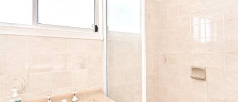A bathroom with a sink, two faucets, a soap dispenser, and a mirror.