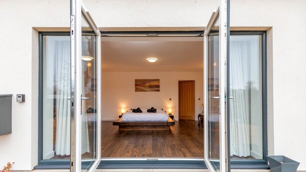 Un dormitorio con una cama grande, puertas de vidrio corredizas y vistas al exterior.