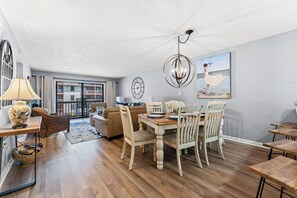 A dining area with a wooden table and chairs, a chandelier, and a painting on the wall.