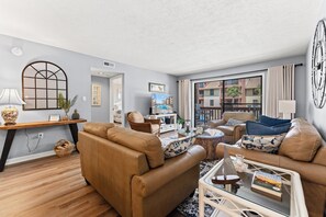 A living room with a sofa, armchair, coffee table, and a large window with a view of buildings. - Anchorage II 205  Lovely 2 Bedroom Condo With Great Ocean Views and Outdoor Swimming Pool (MYRTLE BEACH)