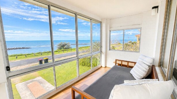 Quarto com uma grande janela com vista para a costa.