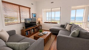 A living room with a flat-screen TV, a bookshelf, and a sofa set.