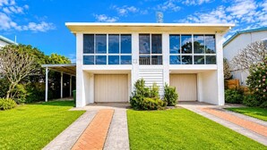 Uma casa de dois andares com garagem, varanda coberta e gramado bem cuidado.