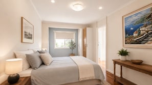 Una camera da letto con un letto, un comodino, una lampada e un quadro appeso al muro.