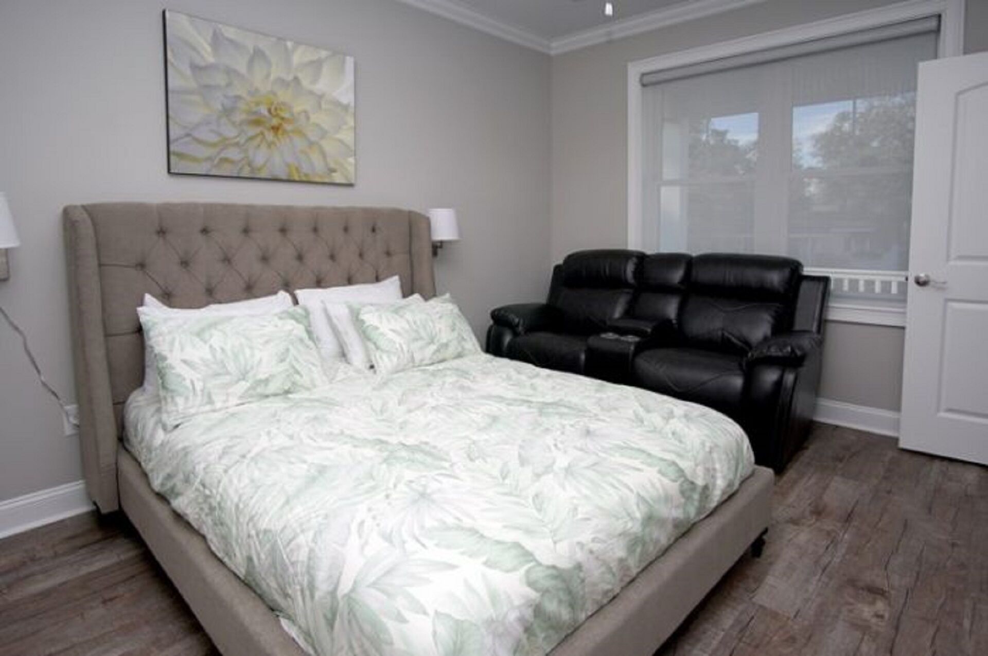 A bedroom with a bed, a massage chair, and a window.