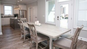 A kitchen with a large island, wooden chairs, and a light-colored table.