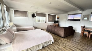 A room with two beds, a sofa, a TV, and a dining table.