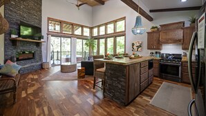 Una cocina amplia con una isla grande, armarios de madera y una chimenea de piedra.