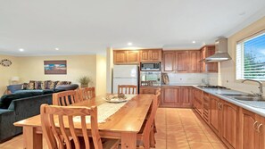 Una cocina moderna con armarios de madera, un comedor con mesa y sillas, un refrigerador y una estufa.