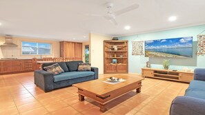 A spacious living area with a sofa, coffee table, and a TV mounted on the wall.