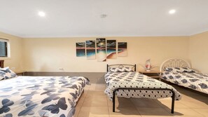 Un dormitorio con dos camas, una mesita de noche, una lámpara de pared y un ventanal.
