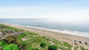 A beach with a parking lot and a road leading to the beach.