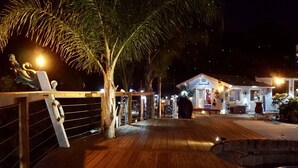 Une terrasse en bois avec un palmier, une petite piscine et un bâtiment portant une enseigne.