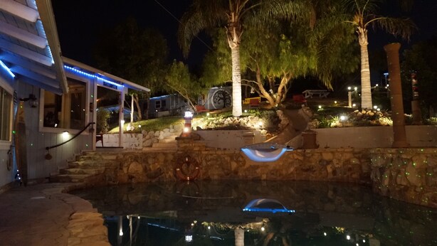 Une piscine bordée de pierres, un vélo et une petite fontaine.